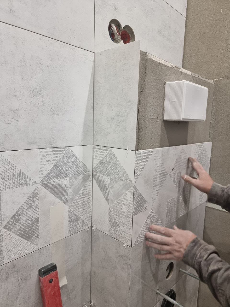 Installer setting wall tile by hand during a bathroom renovation in Calgary