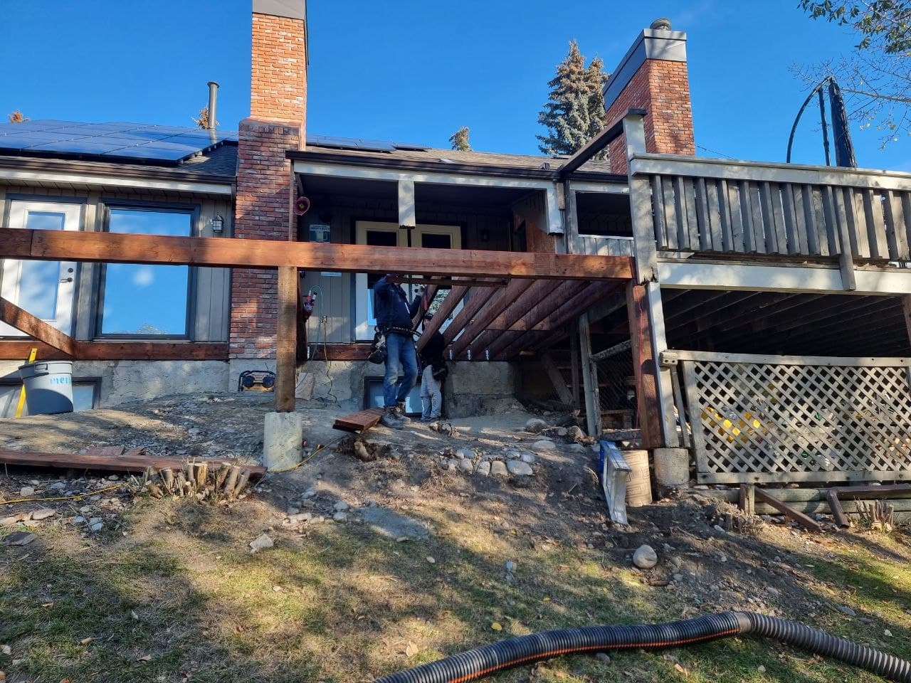 Crew rebuilding a raised backyard deck frame on a Calgary home