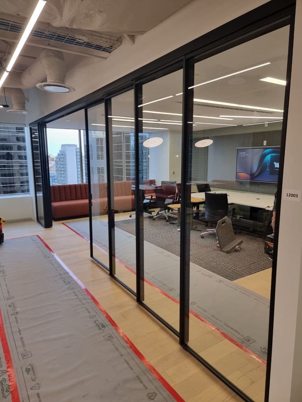 Completed glass-walled meeting room with city views behind black-framed sliding glass — Calgary
