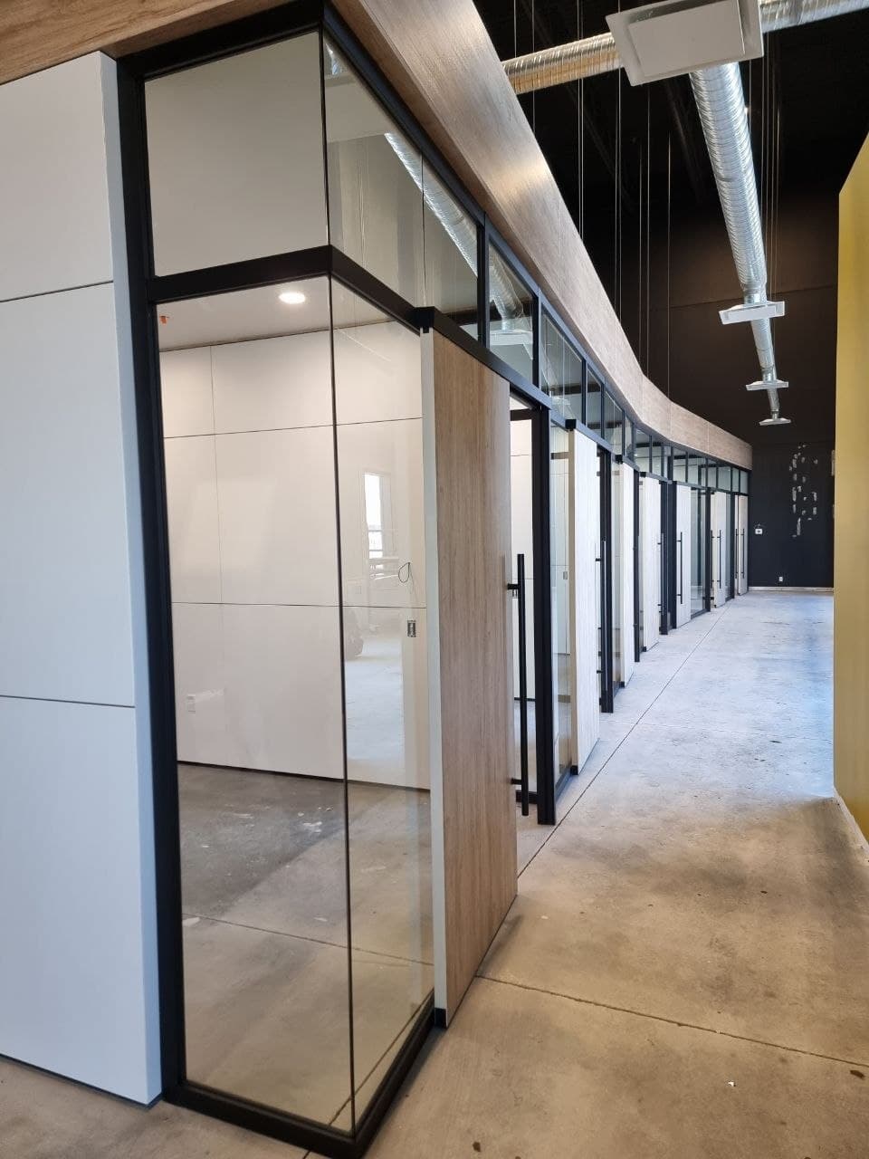 Curved run of glass and wood office partitions with black frames