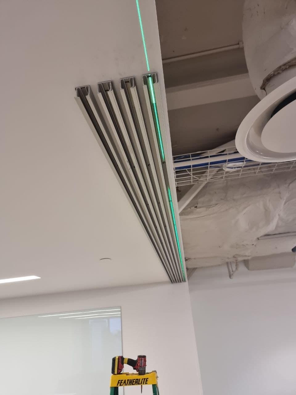 Laser-levelling the ceiling track for a precise office door and glass partition install — Calgary