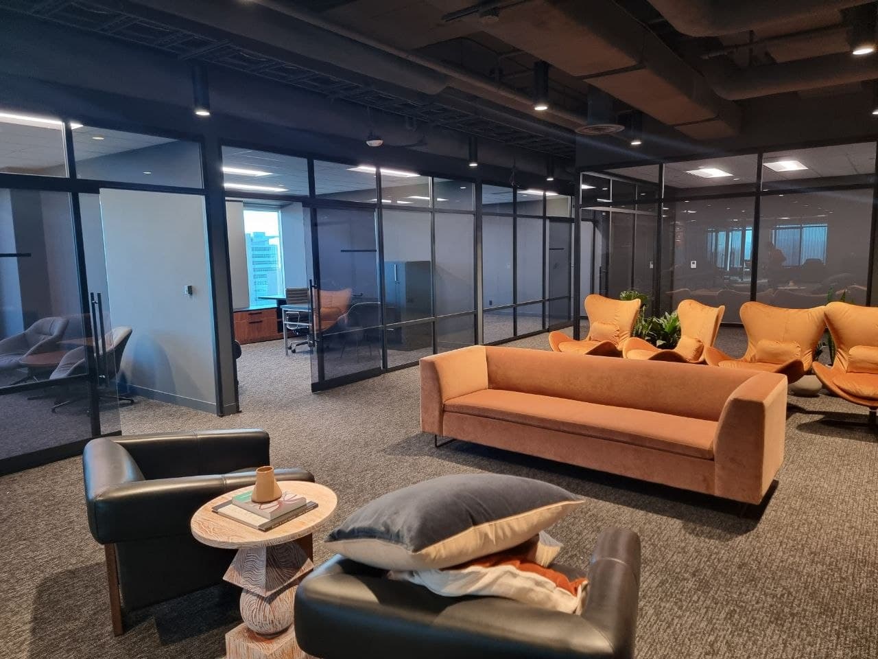 Lounge seating beside black-framed glass private offices in a Calgary workspace