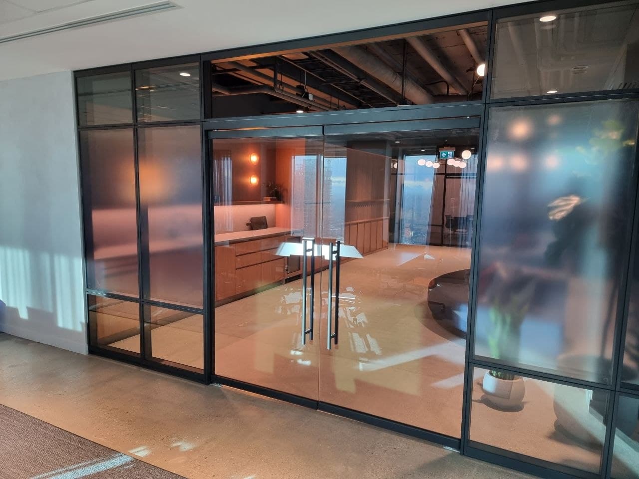 Glass meeting room with a wall screen and wood-grid ceiling — Calgary office fit-out