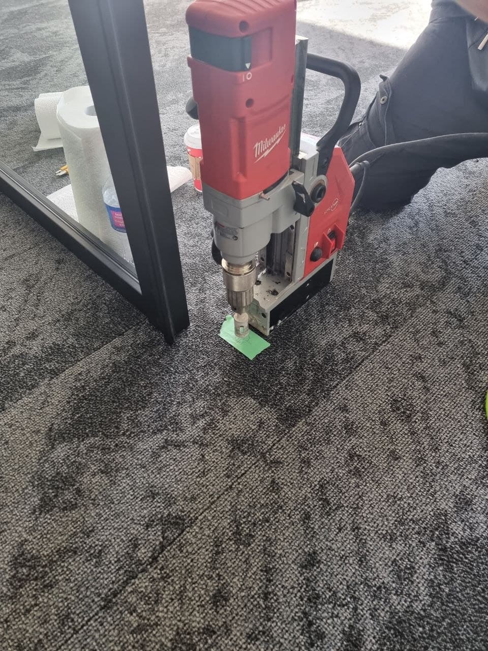 Core-drilling the floor anchor with a Milwaukee rig to set a door and glass partition track — Calgary