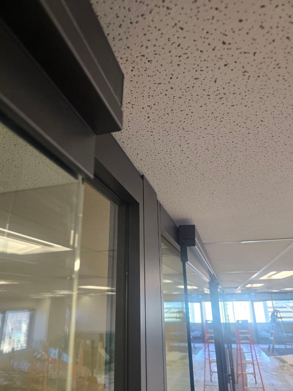 Head track of a newly installed glass office door meeting the ceiling — Calgary door installation